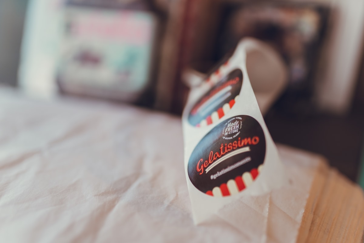 A roll of printed die-cut labels lifting off its release liner, showing the adhesive edge