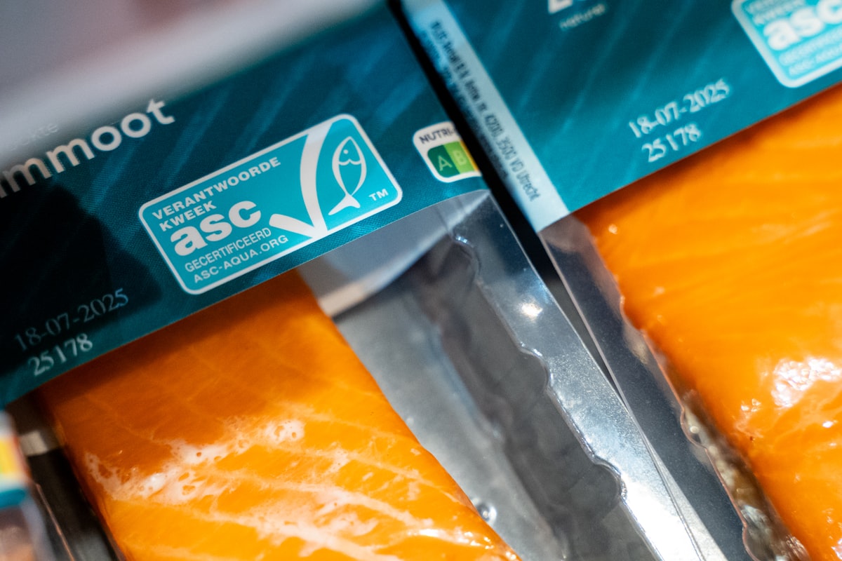 Chilled packaged fish fillets in a refrigerated case with certification and date-code labels