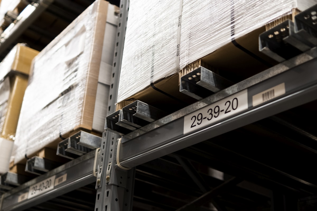 Warehouse pallet racking with barcoded rack-location labels on the beams and shrink-wrapped cartons